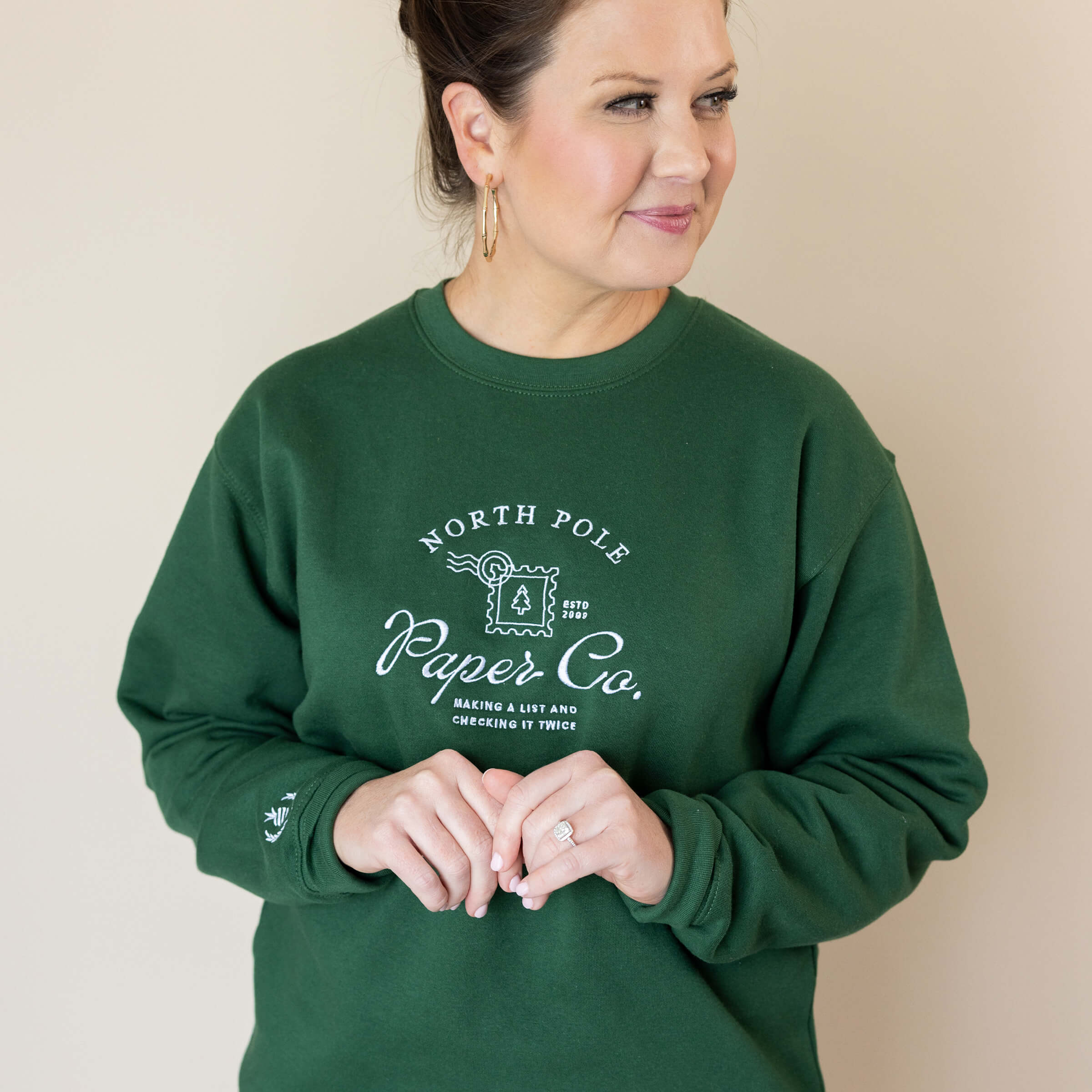 A woman in a hunter green Embroidered Crewneck – North Pole Paper Co. from the Simplified® by Emily Ley collection.