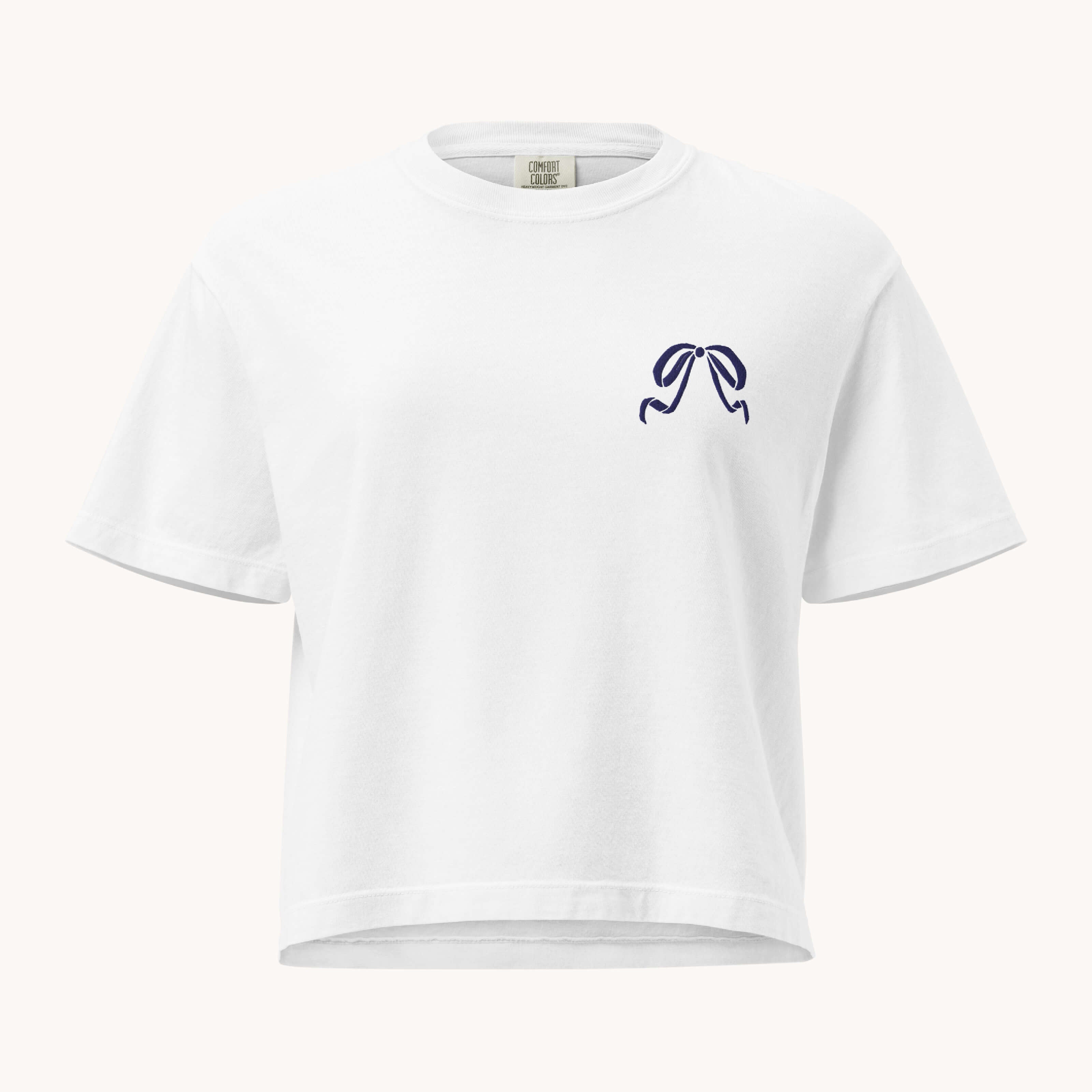 The Boxy T-Shirt - Embroidered Bow by Simplified is a white, short-sleeve, 100% cotton tee featuring a small navy blue bow embroidered on the left chest.