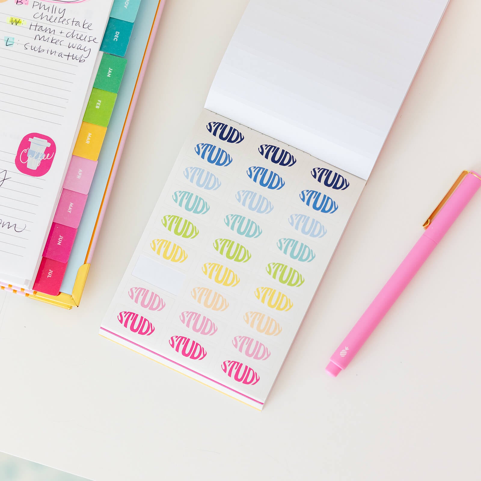 The Simplified Sticker Book - College sits on a desk beside a pink pen and a planner with rainbow tab dividers, perfect for customizing your handwritten to-do list.