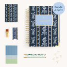 The Daily Simplified Planner Ultimate Bundle by Simplified® features a navy floral planner, matching notebook, bookmark, pens, stickers, gold paper clips & USB drive neatly arranged with a Bundle & Save label in the top right corner.
