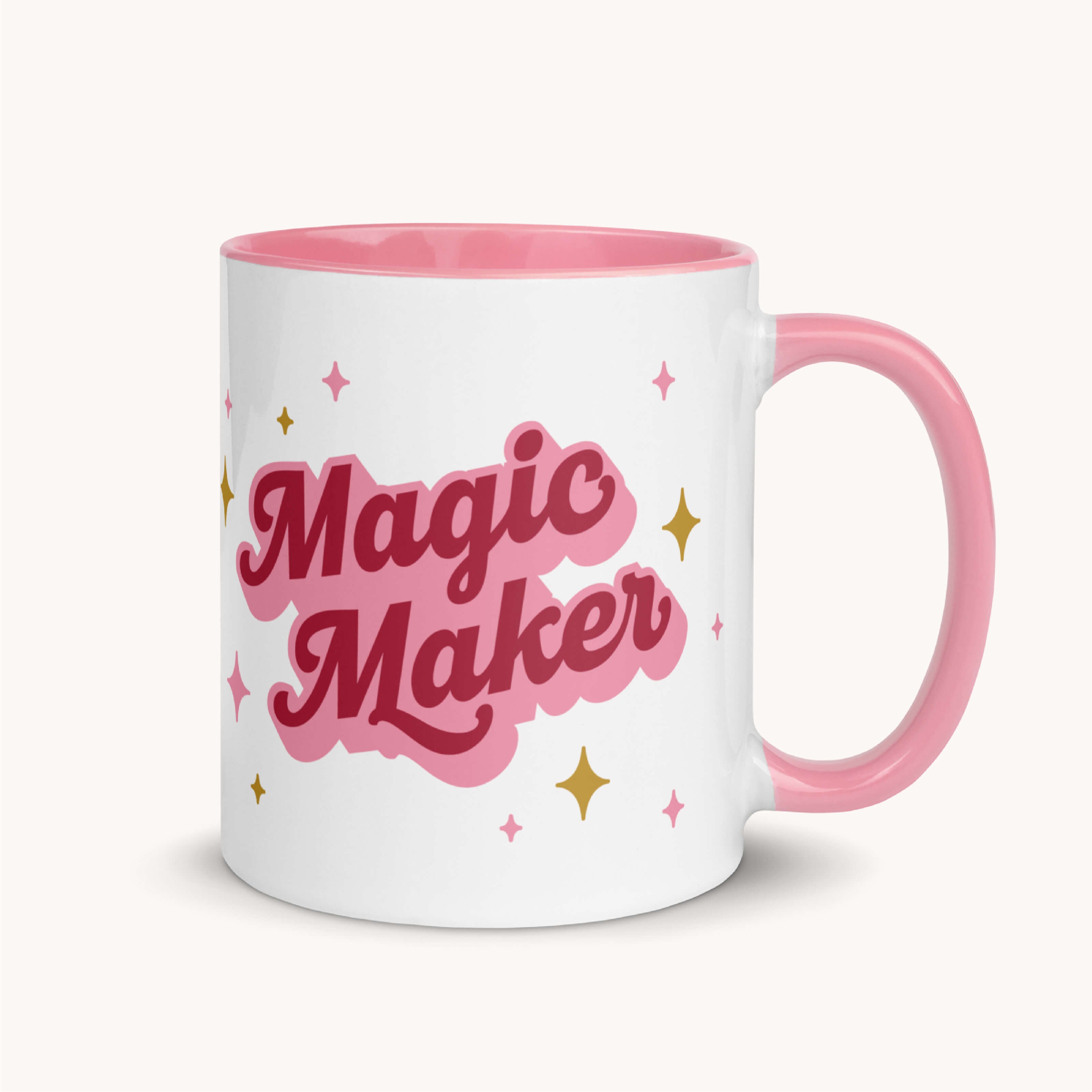 The Simplified Mug - Magic Maker is a white 11 oz ceramic mug with a pink handle and rim, bold pink "Magic Maker" lettering, and gold stars. Microwave safe, it brings daily inspiration to your routine.