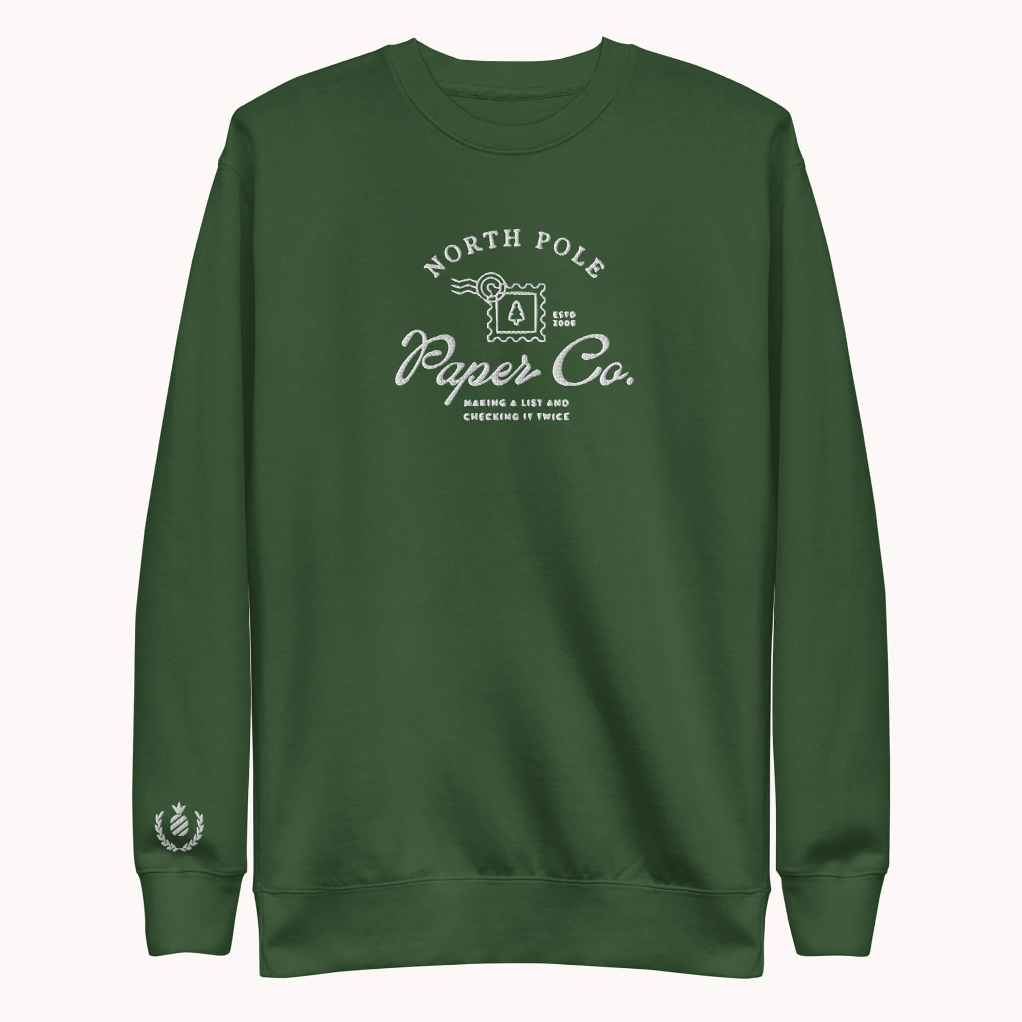 The Simplified® by Emily Ley Embroidered Crewneck - North Pole Paper Co is a hunter green holiday sweatshirt with white text, a mailbox design, "Making a list and checking it twice," and a small laurel wreath on the sleeve cuff.