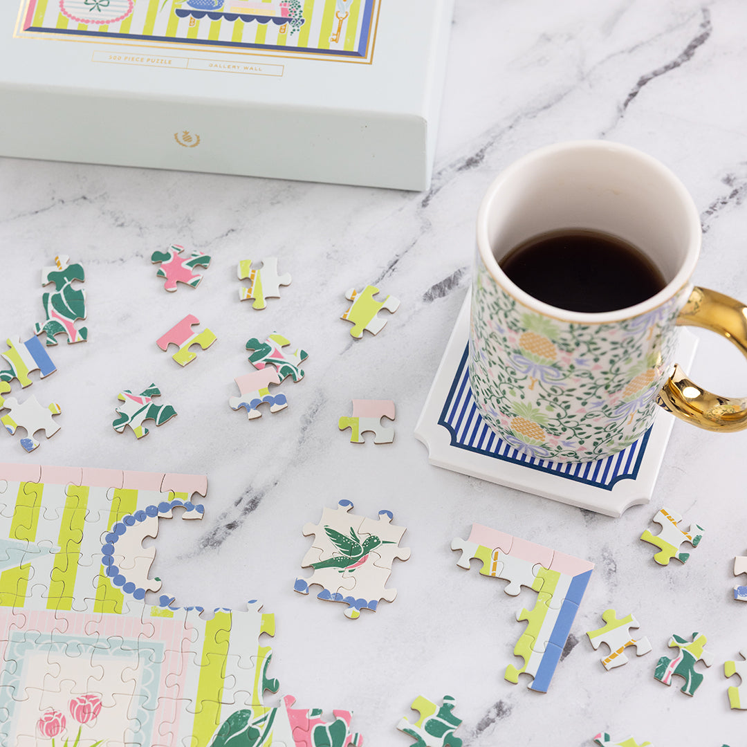Gallery Wall puzzle pieces on a marble surface with a mug of coffee.