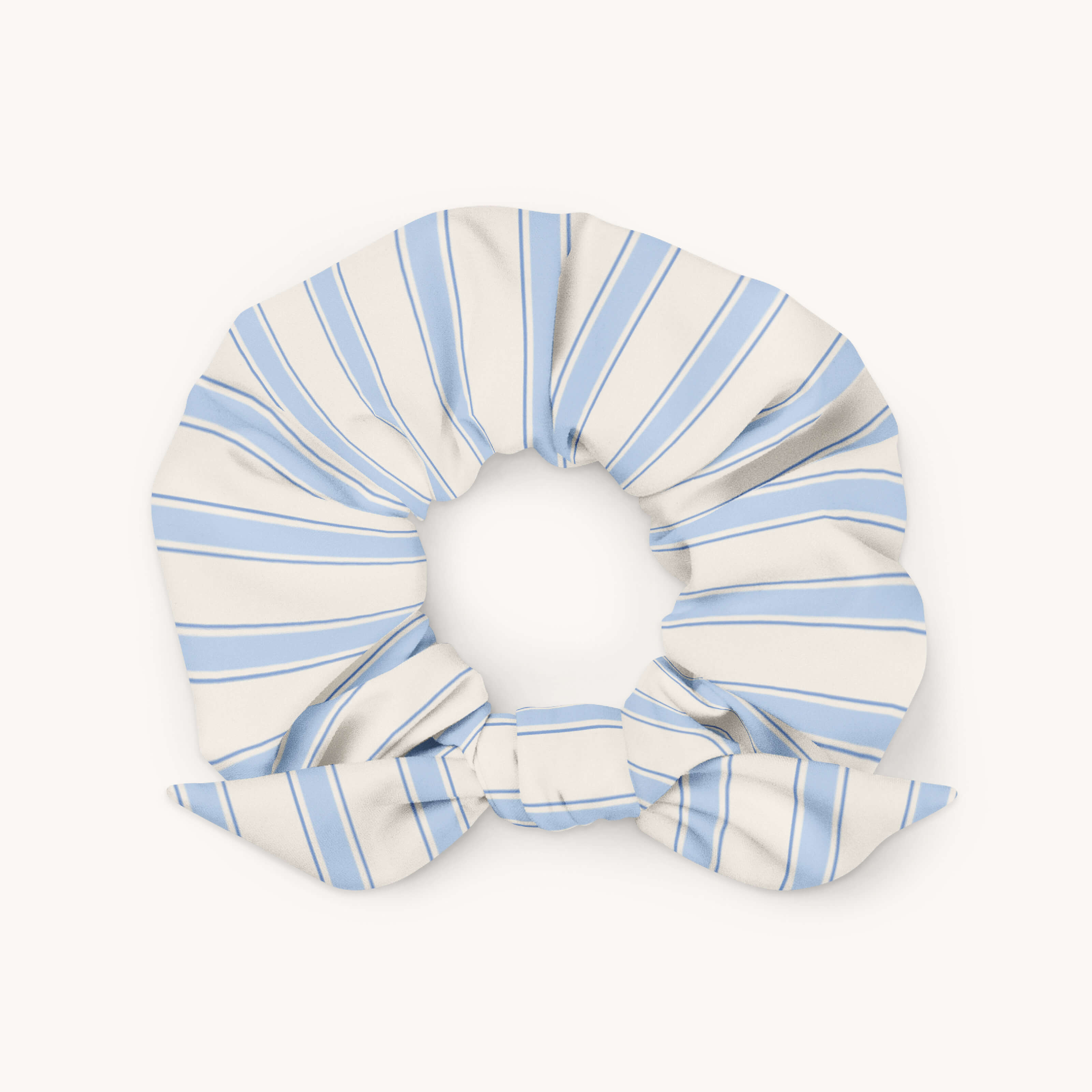 The Simplified Scrunchie - Serene Stripe features light blue and white microfiber stripes with a small bow, displayed in a circular shape on a plain light background.