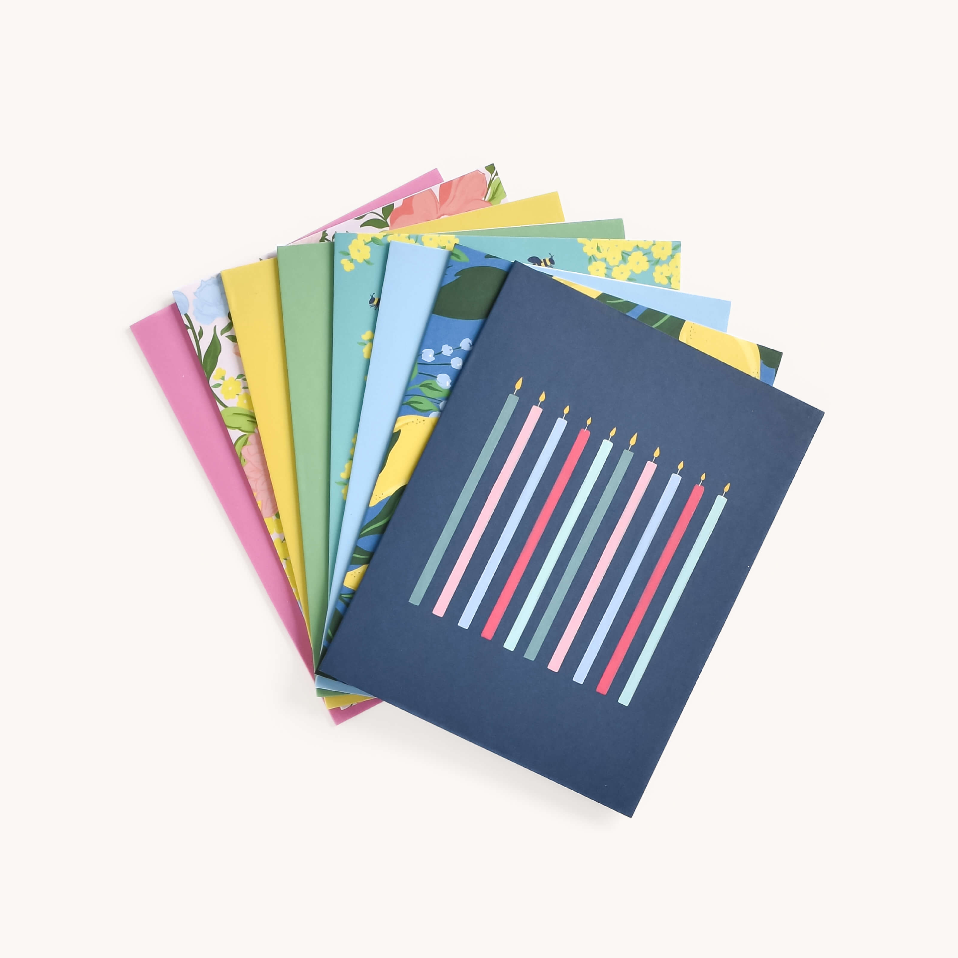 The Card Set - Everyday by Simplified displays a fan-shaped, vibrant arrangement with the top card featuring a blue background and candle-like vertical lines. Below, cheerful cards boast floral designs and pastel shades.