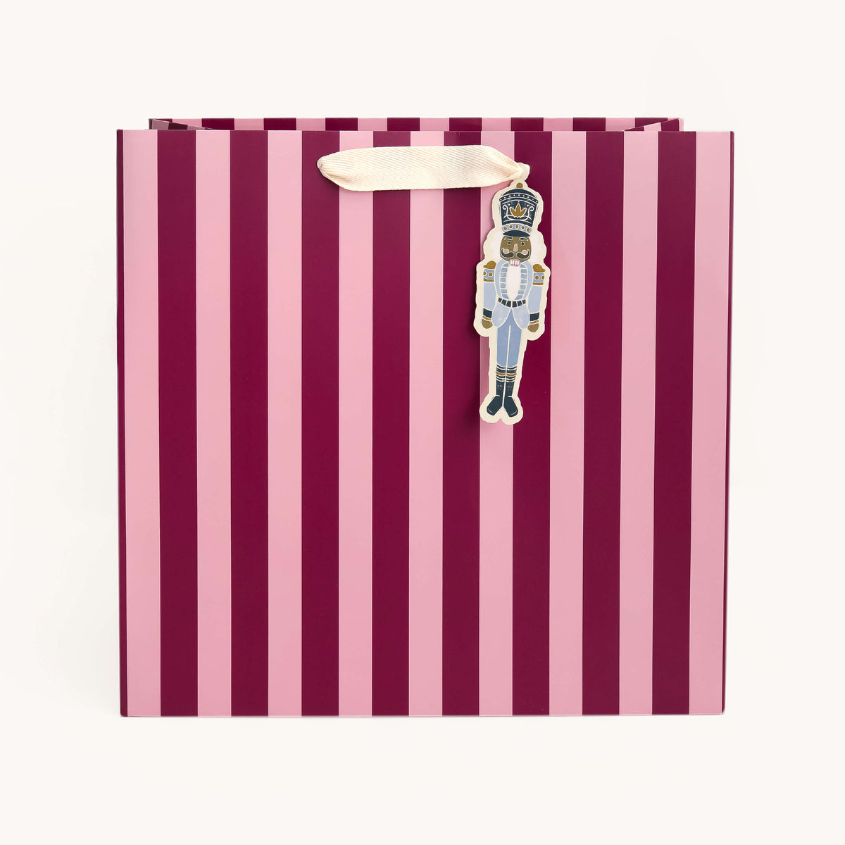 Berry Stripe Large Gift Bag in berry and pink stripes with an ivory ribbon handle and a blue Nutcracker gift tag