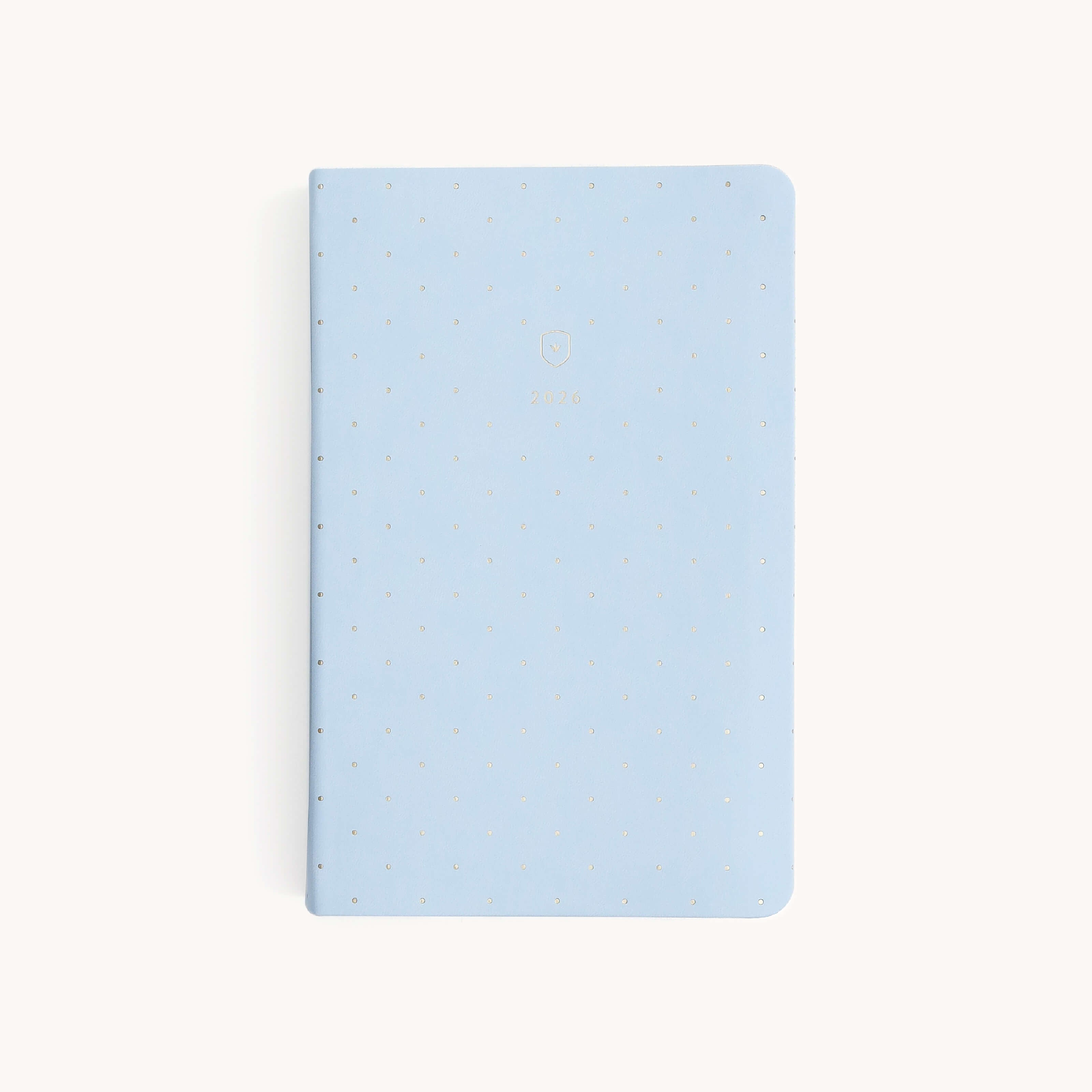A closed Simplified 2026 Bookbound Daily Dapperdesk Planner in Carolina Dot, featuring a light blue leatherette cover with small gold dots, is displayed on a plain white background.