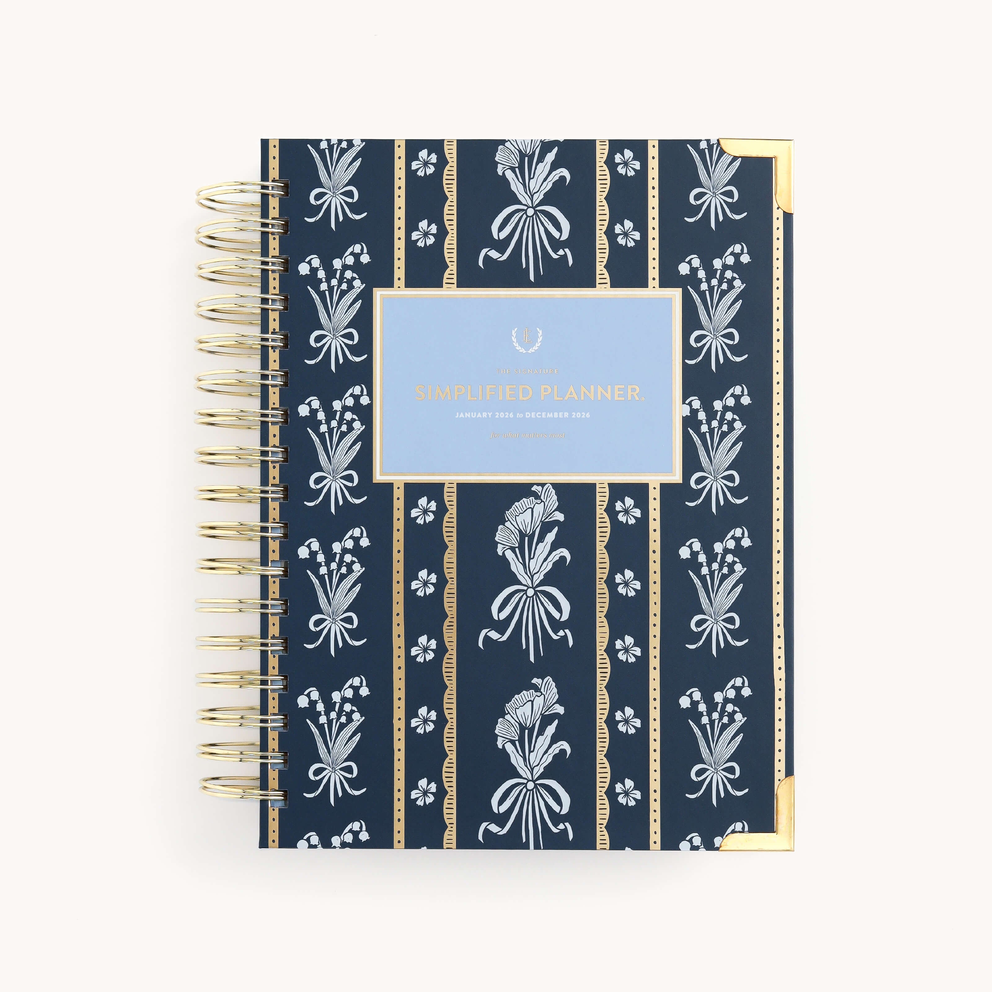 The 2026 Spiral Daily Simplified Planner - Poppy Posies by Simplified features navy blue with white florals, gold corners, and a light blue Simplified Planner label—an elegant choice for your next daily planner.
