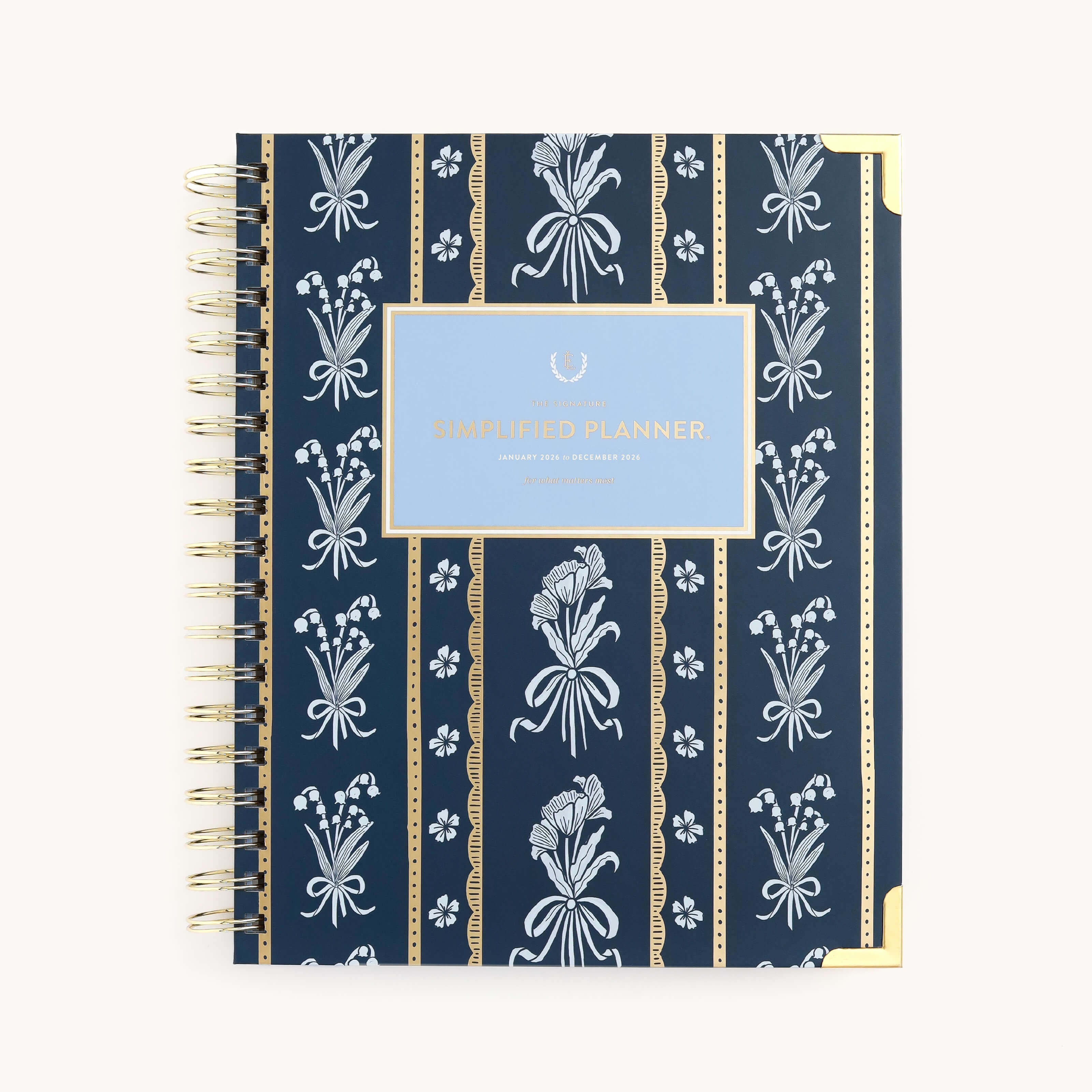 The 2026 Spiral Weekly Simplified Planner - Poppy Posies by Simplified features a navy cover with white floral and stripe patterns, gold corners, and a central blue label—a stylish choice for your 2026 planner.