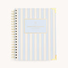 The 2026 Spiral Weekly Simplified Planner - Serene Stripe by Simplified features a light blue and white vertical stripe cover, gold metal corners, and a gold Simplified Planner label—a stylish and functional 12-month planner.