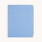 The Simplified Leatherette Folio - French Blue features a leatherette cover, gold metal corners, and a small gold laurel crest in the center, displayed on a plain light background.