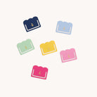 The Index Tab Set - Simplified by Simplified features six scalloped-edge paper clips in navy, light blue, mint green, yellow, pink, and magenta with gold pineapple designs—perfect for planners or metal index tab collections. White background shown.