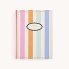 The Simplified Linen Journal - Back and Forth features a hardcover with vertical pastel stripes in pink, green, orange, blue, and white, and a black-edged white oval with gold trim reading Just Between Us in uppercase letters.