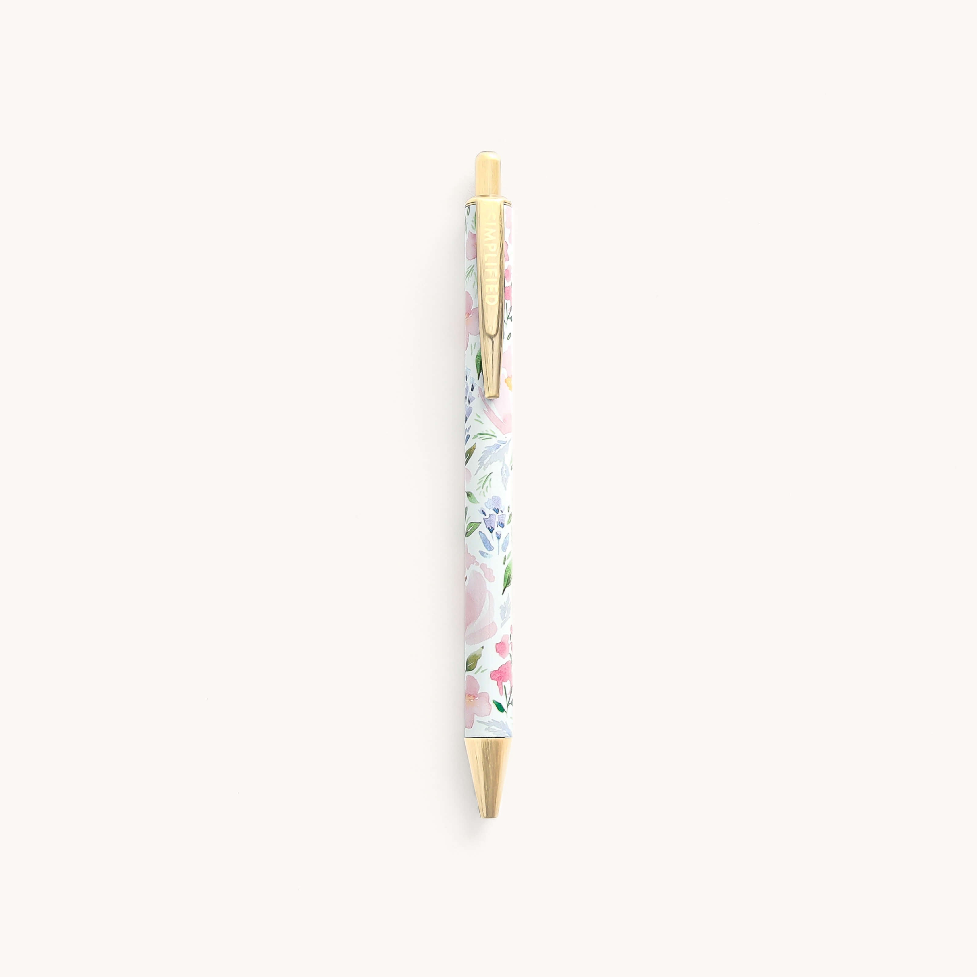 The Click Pen - Cottage Floral by Simplified boasts a refined metal body adorned with a pastel floral design on white, complemented by a gold clip and tip, making it ideal for everyday writing.