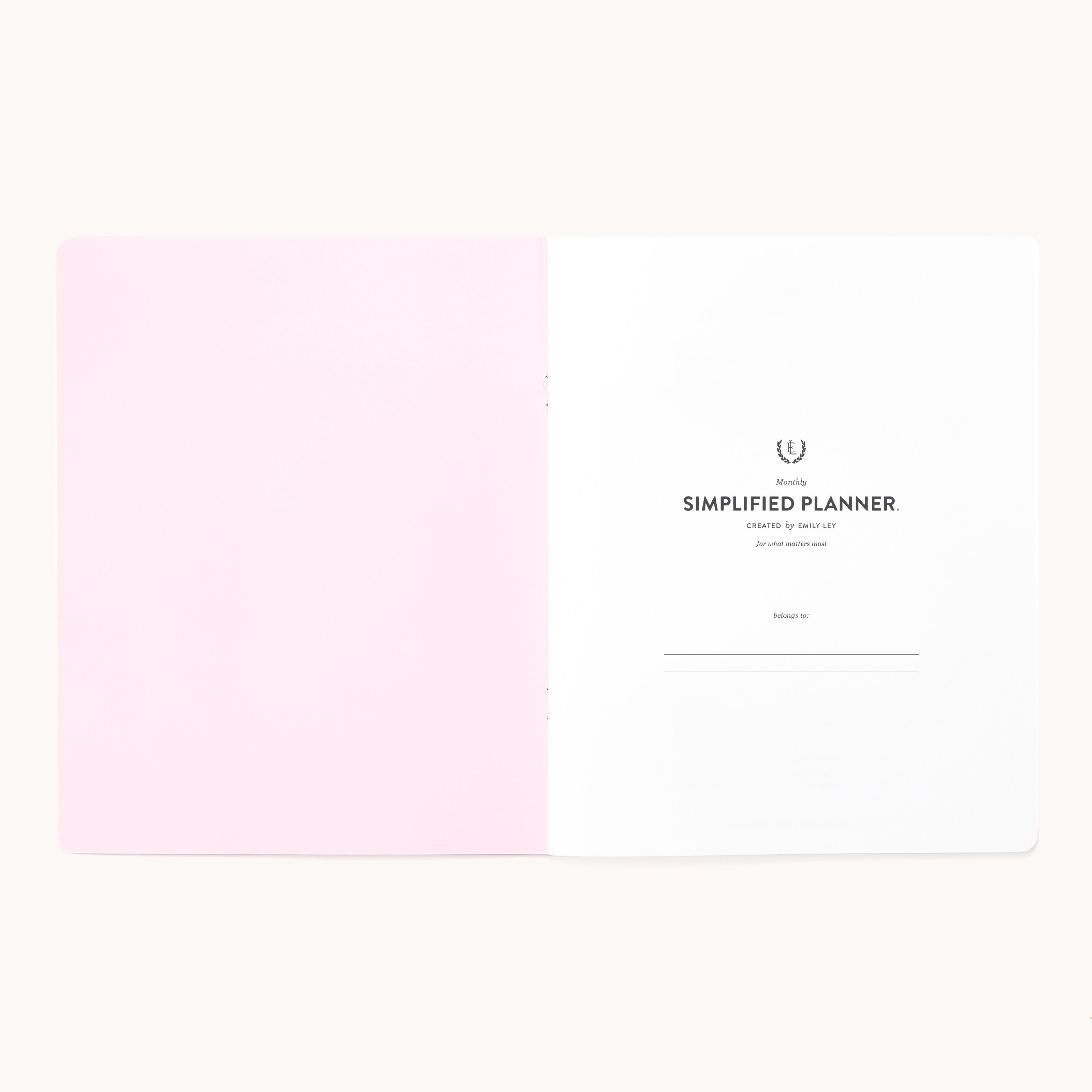 An open 2026 Softcover Monthly Simplified Planner - Happy Stripe by Simplified shows a pink left page and a white right page titled Simplified Planner, with organized, lined spaces for name and date in a minimal, clean layout.