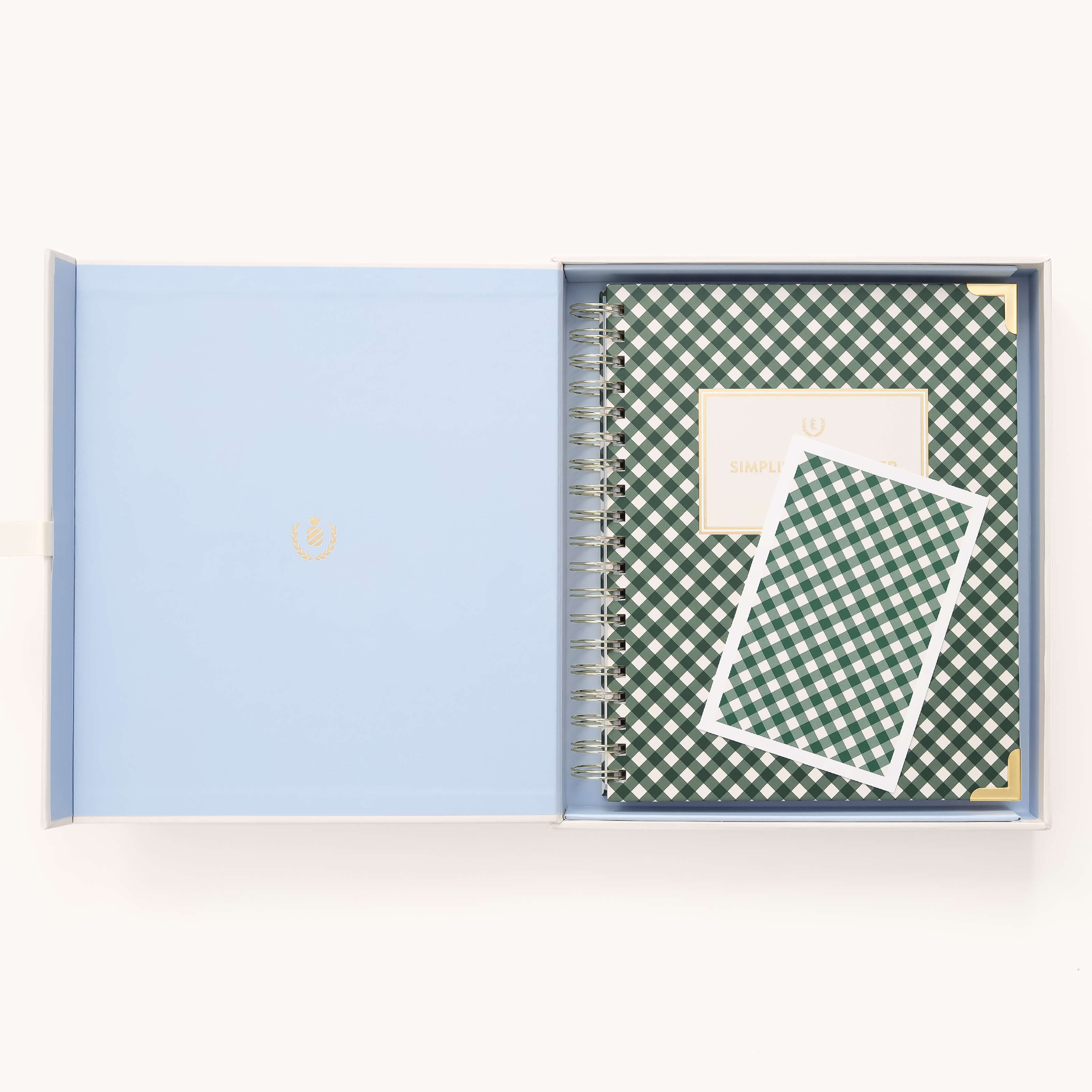 An open light blue box holds the Simplified 2026 Spiral Weekly Simplified Planner - Camp Gingham and a matching card, both featuring a green and white checkered pattern. The planner has a white label on its cover.