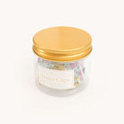A clear jar with a gold lid holds durable, stylish metal binder clips in colorful floral patterns. The label reads Cottage Floral Binder Clips - 6 Brass Clips by Simplified. The jar stands out against a plain white background.