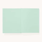 The Simplified Linen Journal - Block Floral lies open on a light, neutral background, revealing its blank pale green pages.