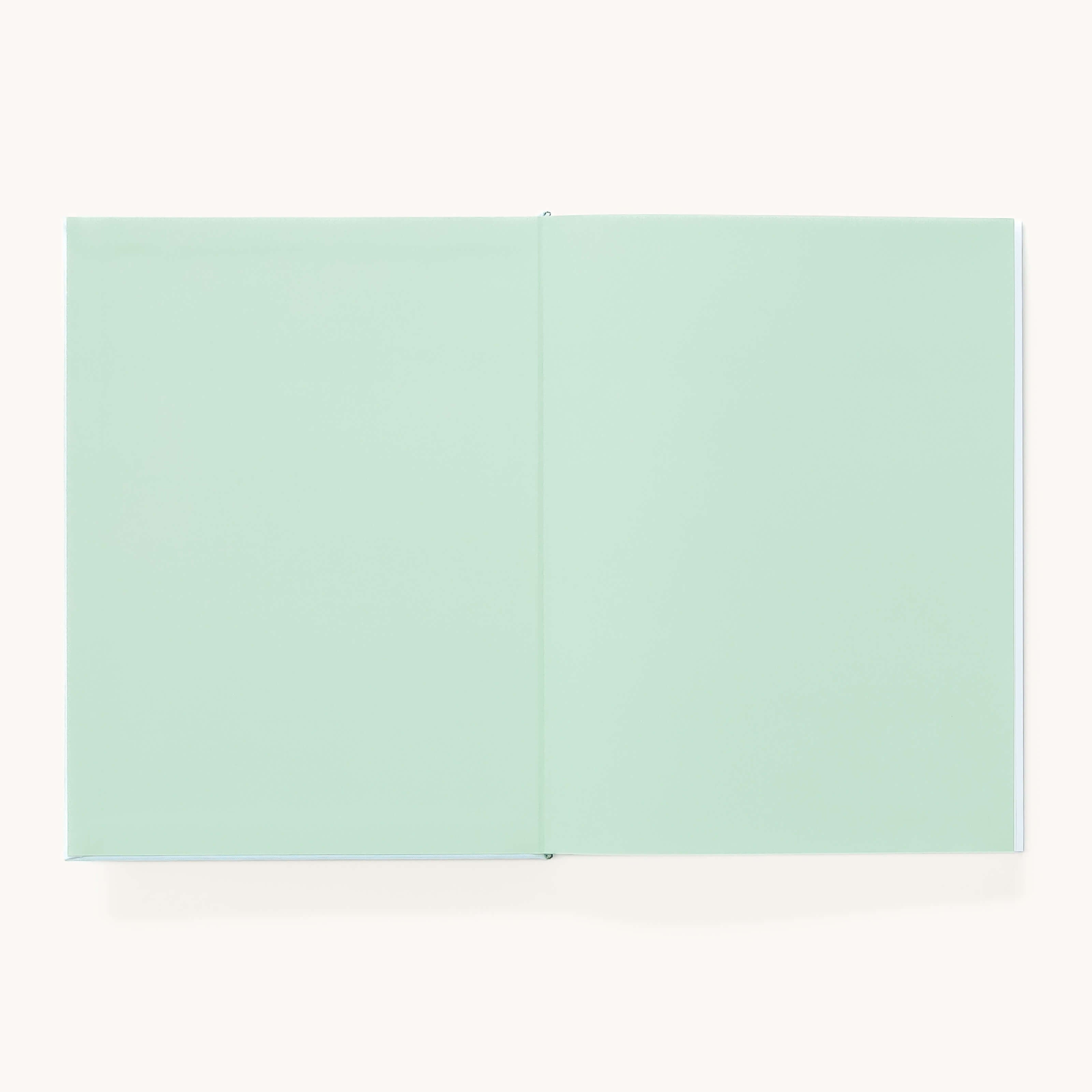The Simplified Linen Journal - Block Floral lies open on a light, neutral background, revealing its blank pale green pages.