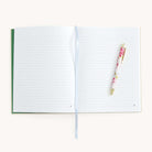 Open journal with lined pages and a floral pen on a white background