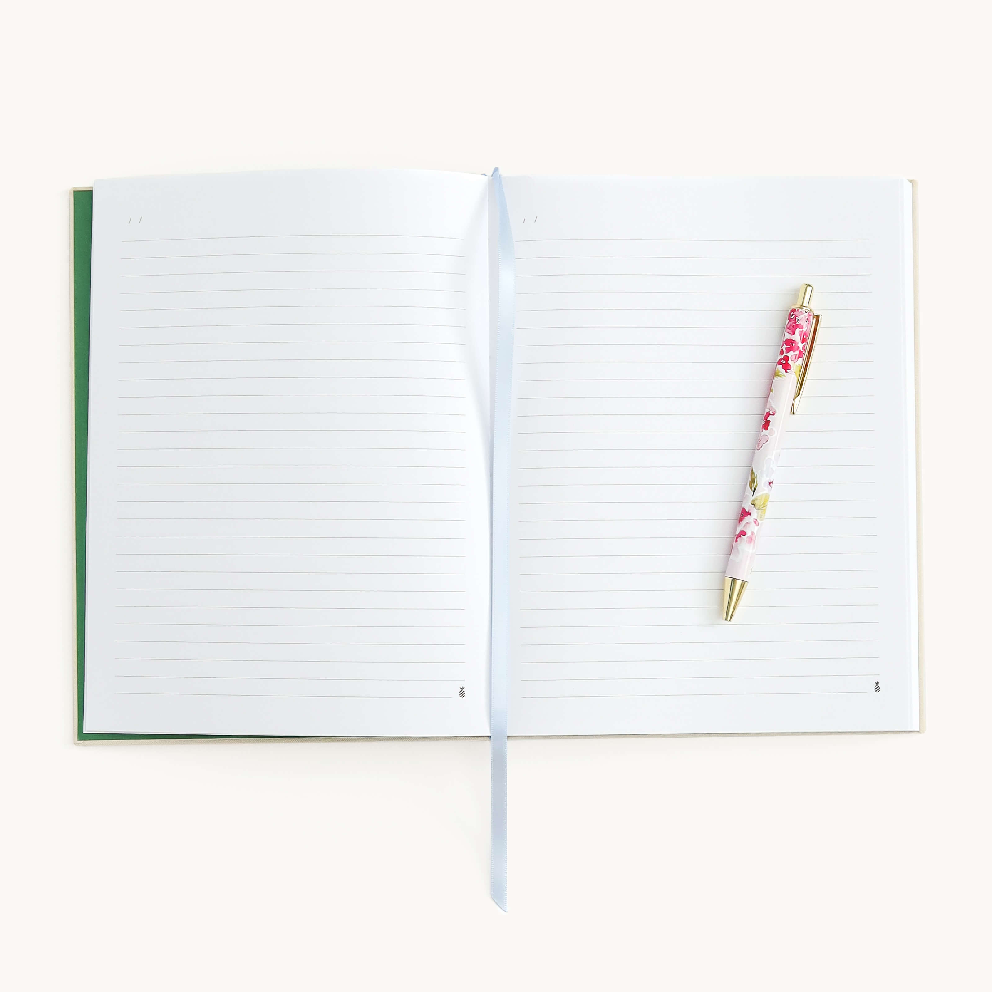 Open journal with lined pages and a floral pen on a white background