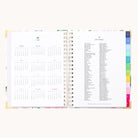 The 2026 Spiral Weekly Simplified Planner - Cottage Floral by Simplified features a year-at-a-glance for 2026 on the left and a 2026 holidays list on the right, highlighted by colorful tab dividers along the edge.