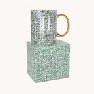 Emerald Floral Ceramic Mug with a gold handle and rim on top of its matching green leaf print gift box
