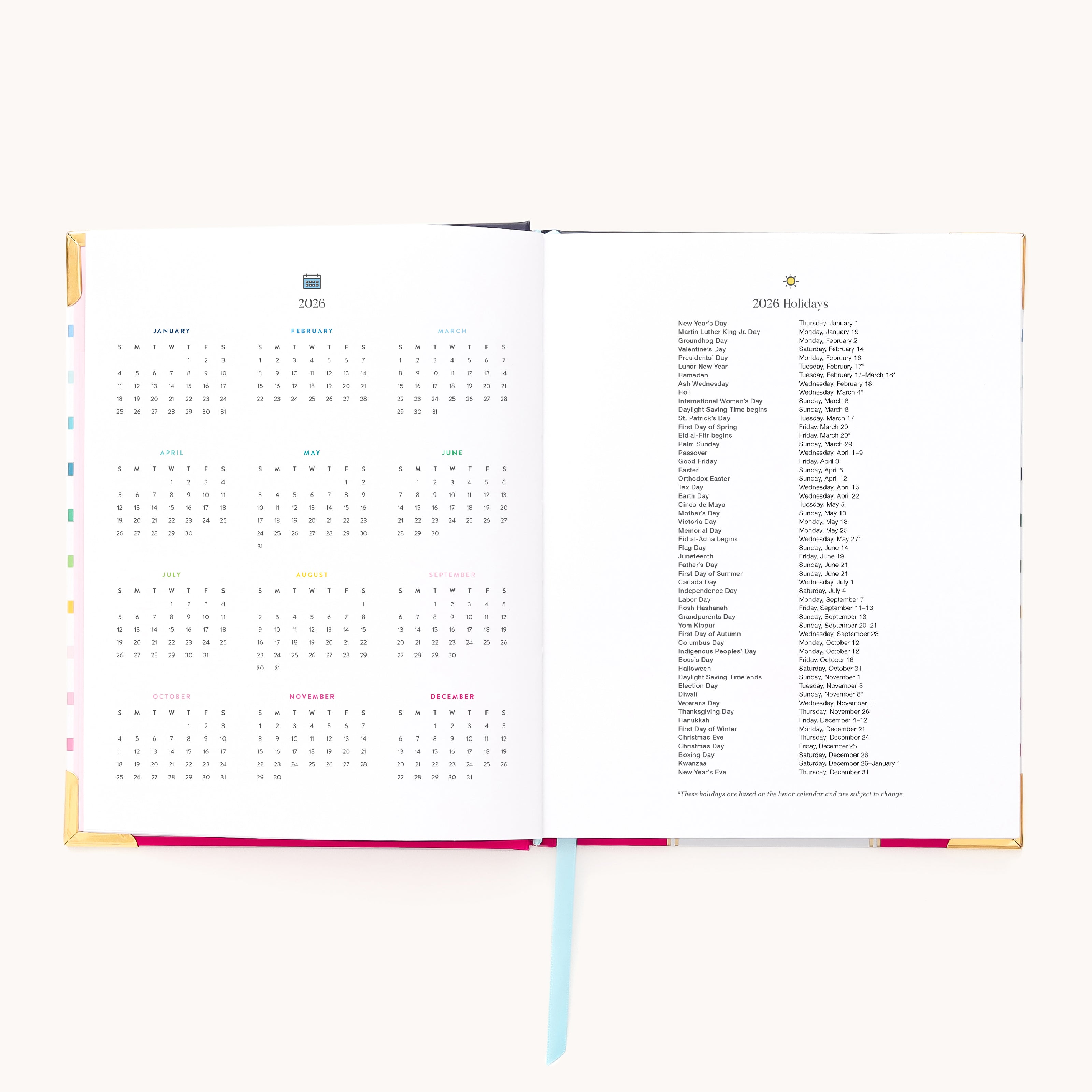The 2026 Bookbound Weekly Simplified Planner - Happy Stripe by Simplified features lay-flat binding, a yearly calendar on the left, 2025 holidays on the right, and is accented with a blue ribbon bookmark at the bottom center.