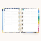 The 2026 Spiral Daily Simplified Planner – Poppy Posies by Simplified is open to Monday and Tuesday daily pages with hourly slots, a notes section, and colorful laminated monthly tabs on an off-white background—ideal for staying organized in 2026.
