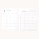 The 2026 Softcover Monthly Simplified Planner - Happy Stripe by Simplified features an open spread with a January 2026 calendar, space for notes on the left, and small overview calendars for December 2025 and February 2026 in the top right.