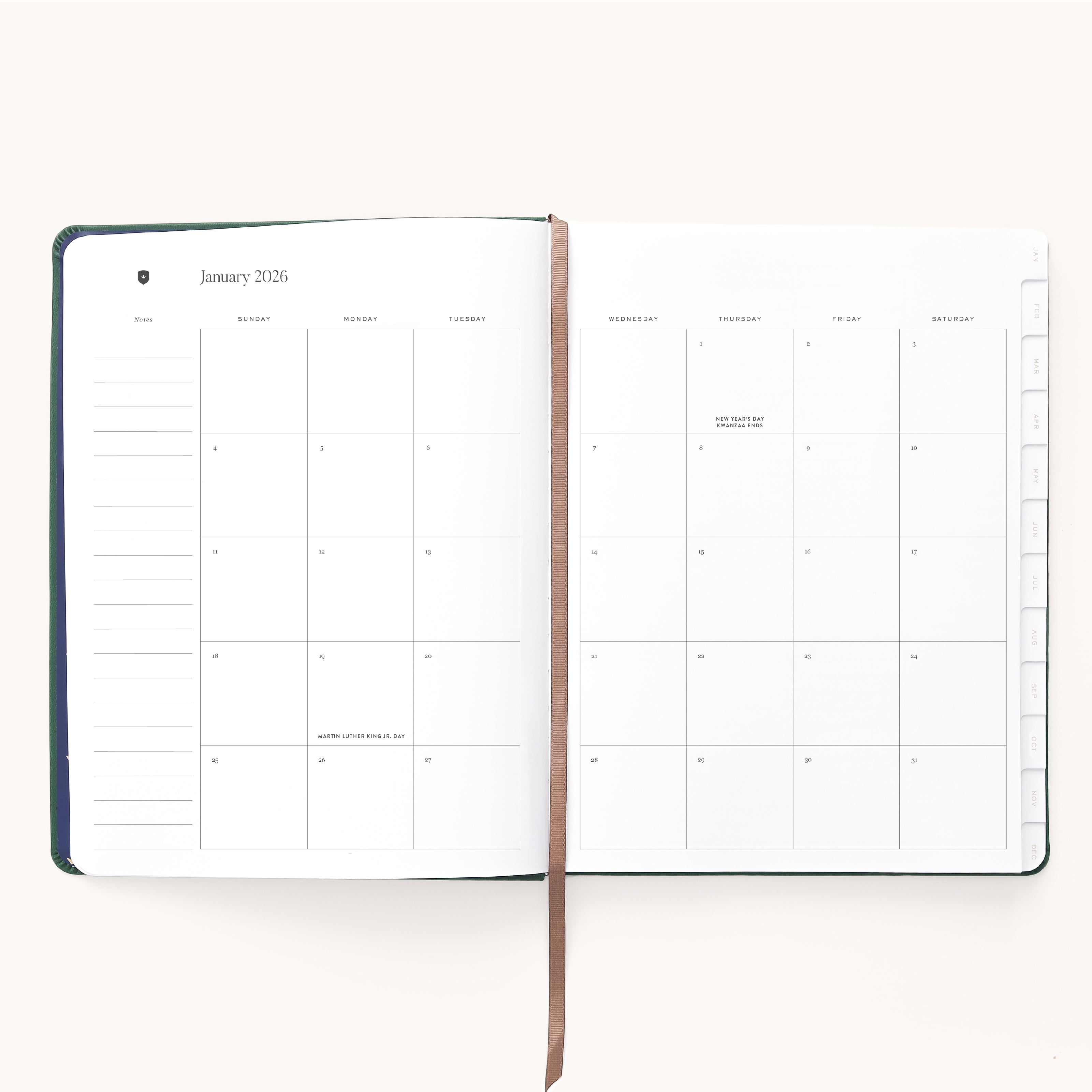 The Simplified 2026 Bookbound Weekly Dapperdesk Planner in Evergreen features a stylish leatherette cover, a ribbon bookmark, and displays January’s monthly calendar with holidays like New Year’s Day and Martin Luther King Jr. Day labeled.