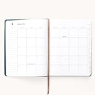 The Simplified 2026 Bookbound Weekly Dapperdesk Planner in Evergreen features a stylish leatherette cover, a ribbon bookmark, and displays January’s monthly calendar with holidays like New Year’s Day and Martin Luther King Jr. Day labeled.
