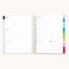 The 2026 Spiral Weekly Simplified Planner - Serene Stripe by Simplified features open pages with dated weekly spreads, lined sections for each day, and colorful tabbed dividers marking each month along the right edge of this 12-month planner.