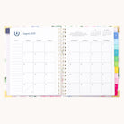 The 2025-2026 Spiral Weekly Simplified Planner - Cottage Floral by Simplified features a monthly calendar for August 2025. Days are in a Sunday to Saturday grid, with gold foil accents on colorful right tabs. A notes section is on the left, and the top right corner has a small calendar for another month.