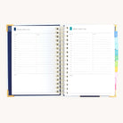 Spiral daily planner open to Monday and Tuesday pages with hourly schedule, to-do lists, and space for notes
