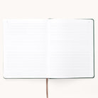 The Simplified 2026 Bookbound Weekly Dapperdesk Planner in Evergreen features a leatherette cover, brown ribbon bookmark, and open lined pages with date spaces in the corners, lying flat on a light surface.