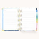 The 2026 Spiral Daily Simplified Planner - Poppy Posies by Simplified rests open on a light surface, featuring lined pages with Notes at the top and colorful tabbed dividers—perfect for organizing your schedule in style.