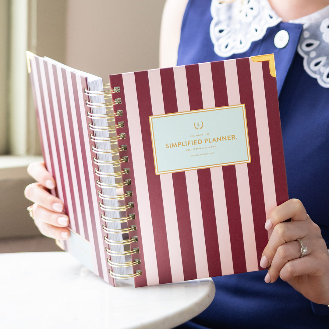 Person holding the spiral daily planner featuring, striped cover, and gold accents for a cheerful, organized life