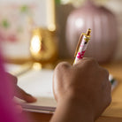 Blush Hydrangea pen held in hand while writing at desk, featuring floral pattern and gold clip for a polished everyday writing experience