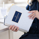 Woman holding Carolina Trellis spiral daily planner with cheerful details for organized daily planning