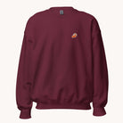 The Simplified Embroidered Crewneck - Sweet As Pie is a maroon pre-shrunk sweatshirt with a small embroidered pumpkin pie slice on the left chest, shown against a plain white background.