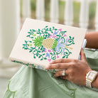 Person holding a journal with floral pineapple embroidery design
