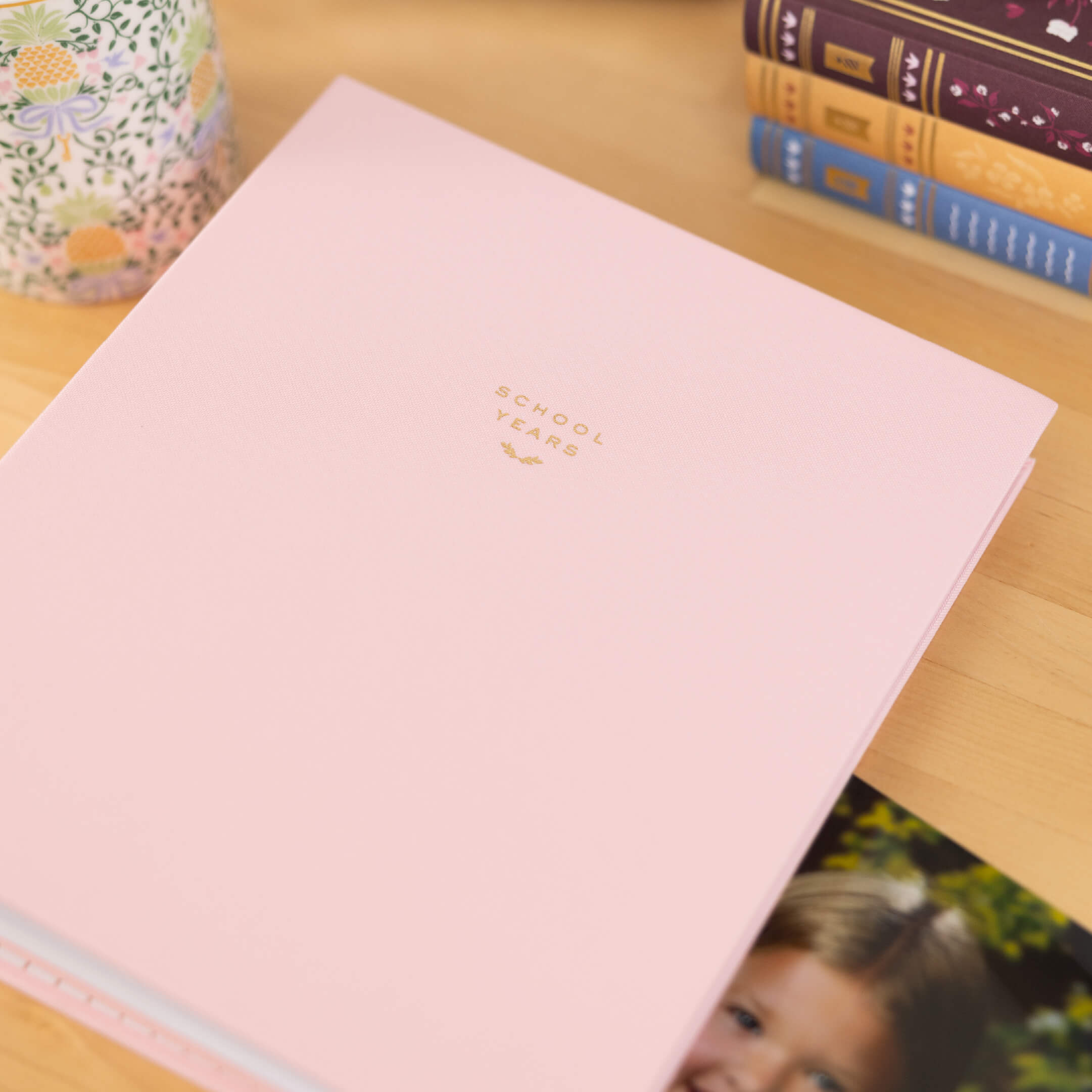 Blush linen School Years Book on a wooden desk.
