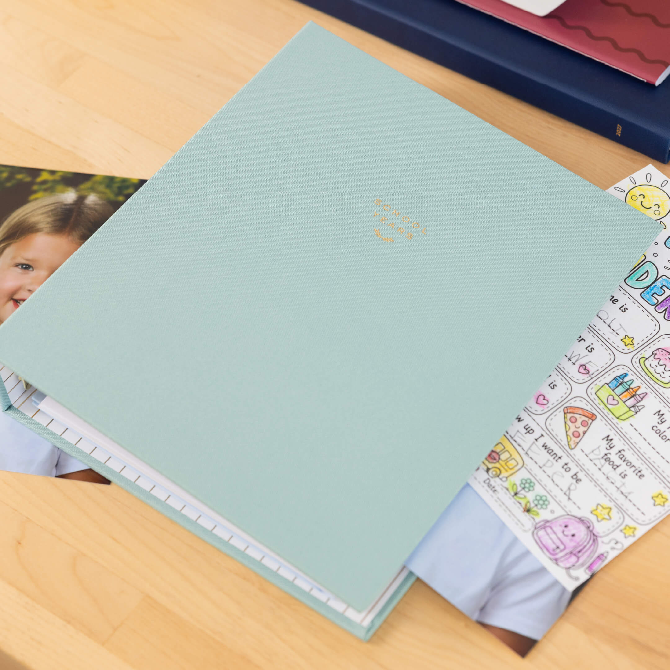 Sage linen School Years Book on a wooden desk.