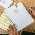 Large softcover weekly planner styled in an elegant workspace for simple, cheerful weekly planning