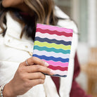 Woman holding Rainbow Row striped passport holder travel wallet by Simplified by Emily Ley