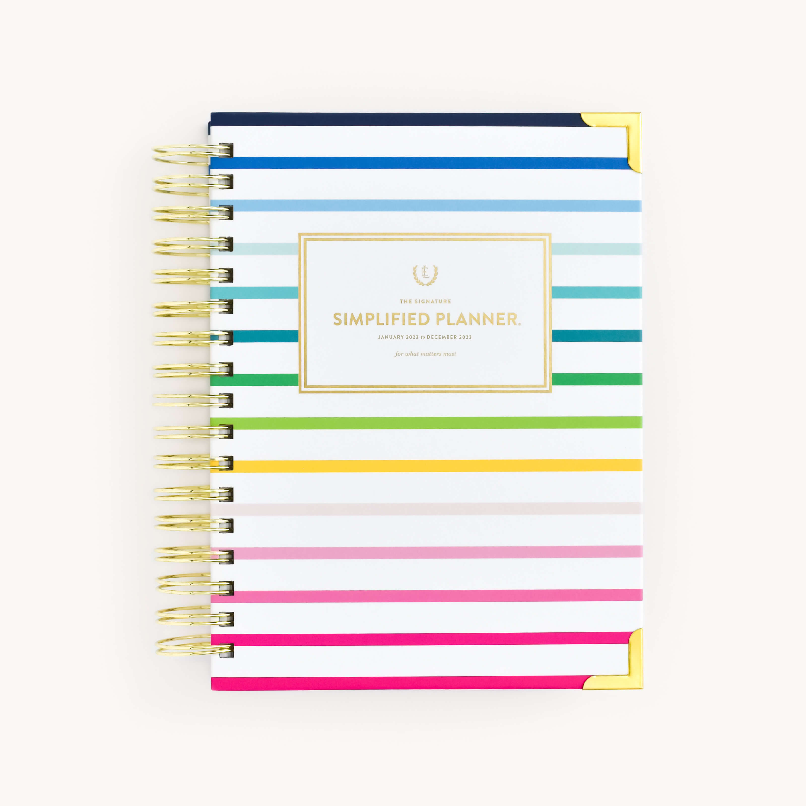 The WS - 2023 Daily, Simplified Planner, Happy Stripe by Simplified® by Emily Ley features a spiral binding, gold corners, and horizontal colorful stripes. The white cover displays "SIMPLIFIED PLANNER" in gold within a gold-bordered rectangle.