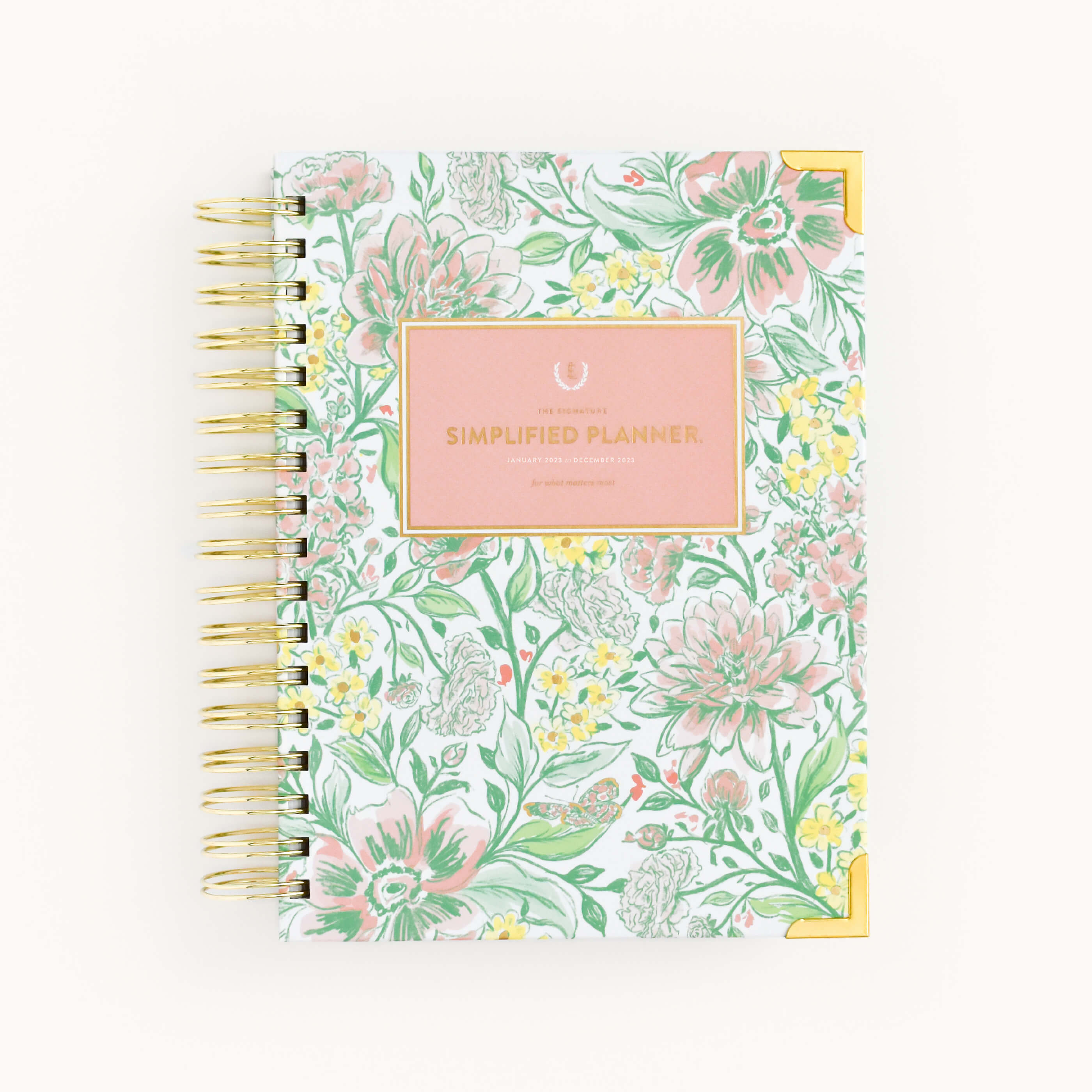The WS - 2023 Daily, Simplified Planner, Butterfly Garden by Simplified® by Emily Ley features a spiral binding, butterfly garden floral cover in green, pink, and yellow with gold corners and a central pink label.